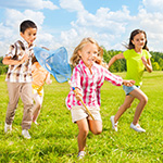 Trois enfants en train de courir dans l'herbe, au soleil d'été.